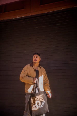 Canvas Tote bag comes in Black or Cream with Streetwear brand logo graphic design screen printed on front side modeled by male model and female model with vintage retro inspiration inspo